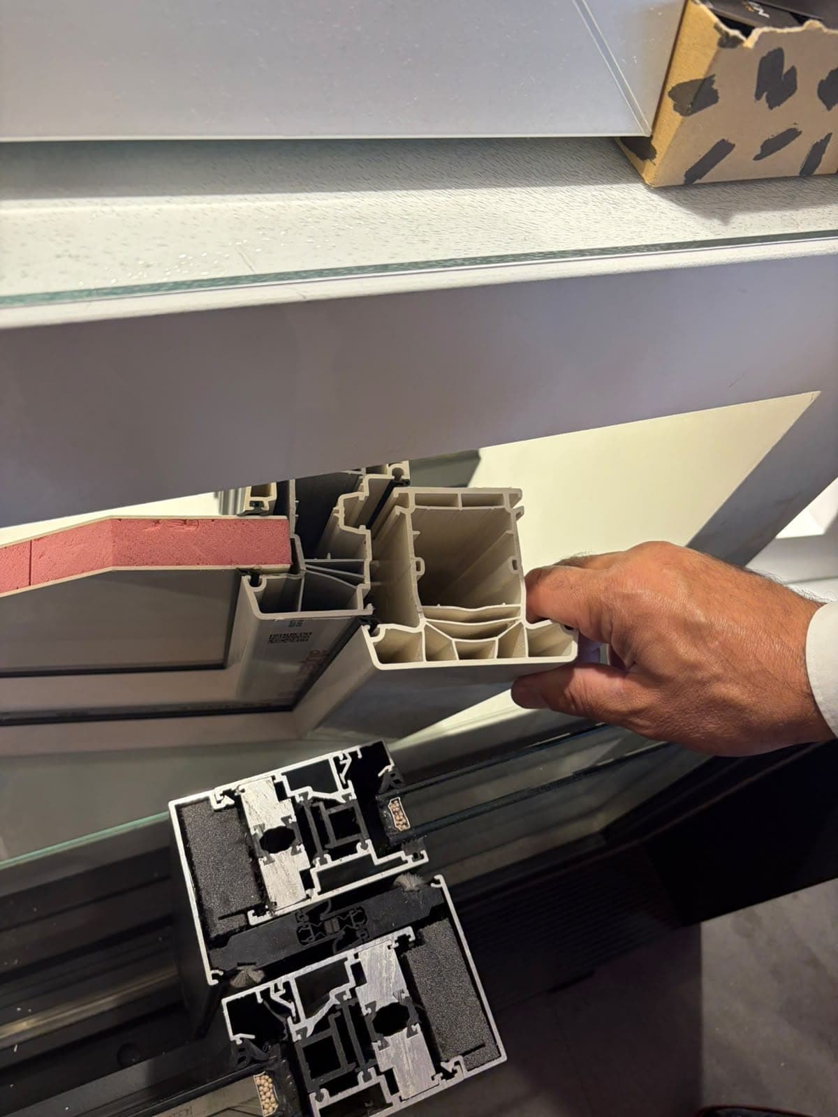 Doorsneden van aluminium kozijnprofielen met zwarte thermische onderbreking, met daarboven een kunststof profiel